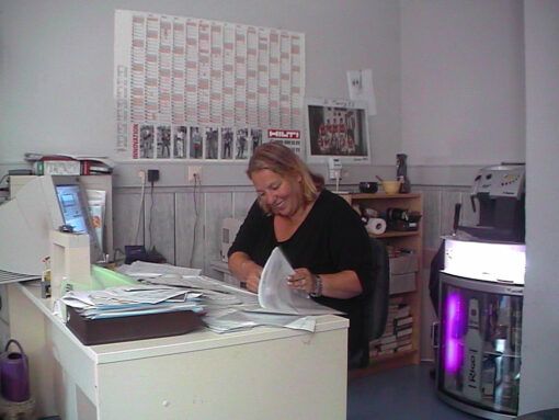 Frau sitzt am Schreibtisch und sortiert Papiere